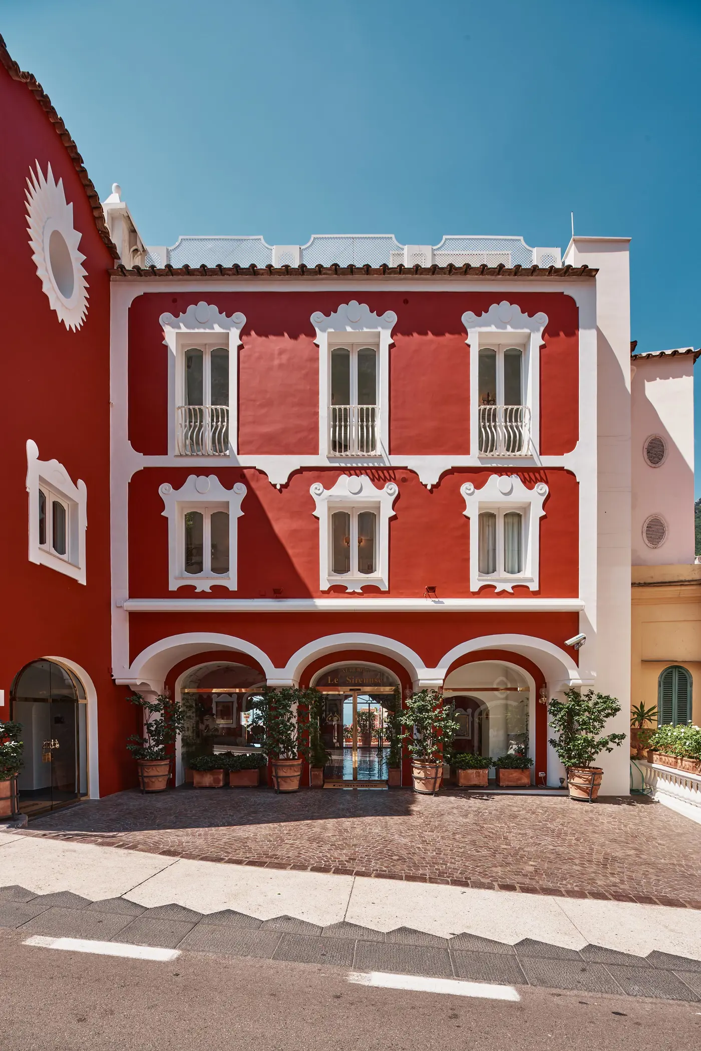 The red and white facade of Le Sirenuse, Positano, under a blue sky